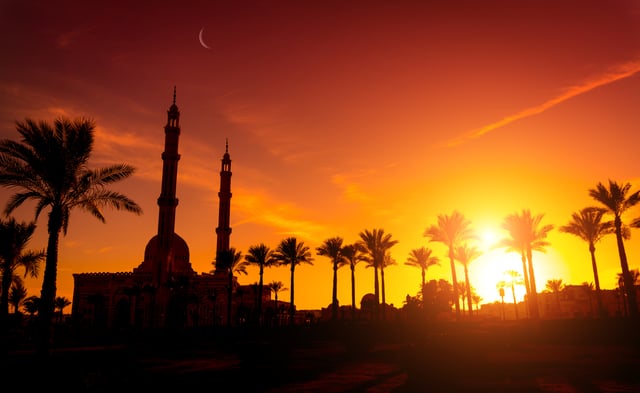 Sunset silhouette of mosque and palms